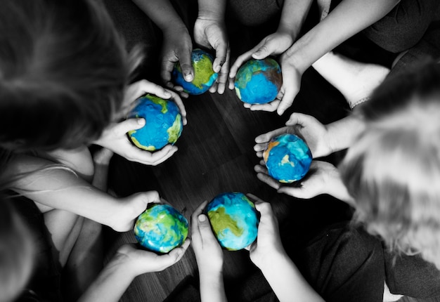 Group of diverse kids hands holding cupping globe balls together