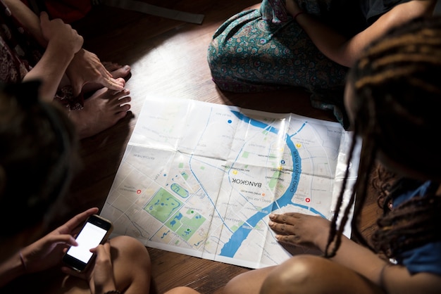 Foto gratuita un gruppo di diversi turisti seduti sul pavimento in legno e la pianificazione della mappa