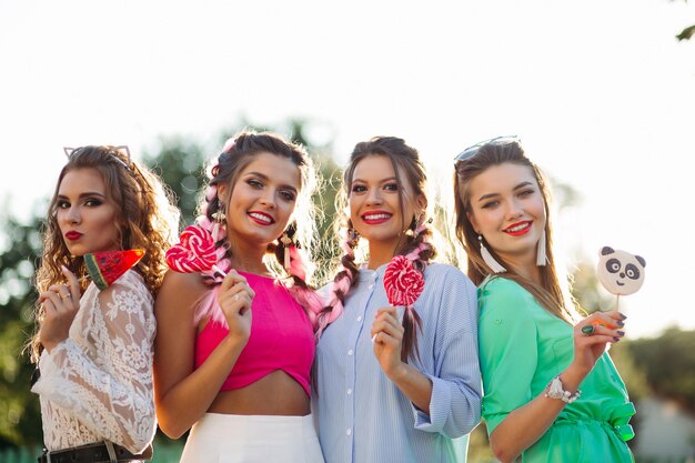 Group of fashionable girls with candies hearts on stick