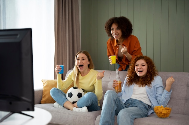 Free photo group of female friends at home watching sports together