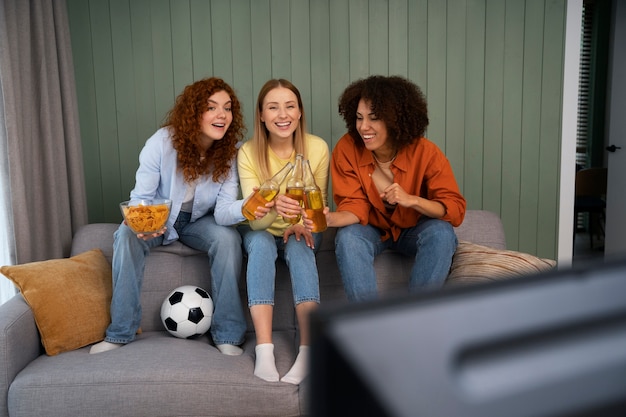 Free photo group of female friends at home watching sports together