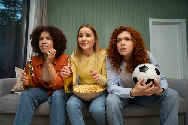 Foto gratuita gruppo di amiche e appassionati di sport che guardano la tv a casa insieme