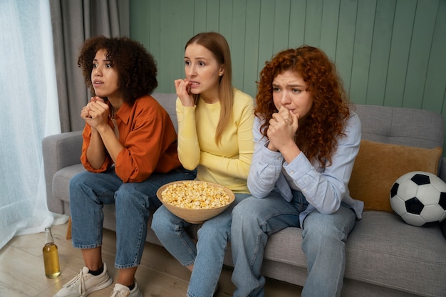 Foto gratuita gruppo di amiche e appassionati di sport che guardano la tv a casa insieme