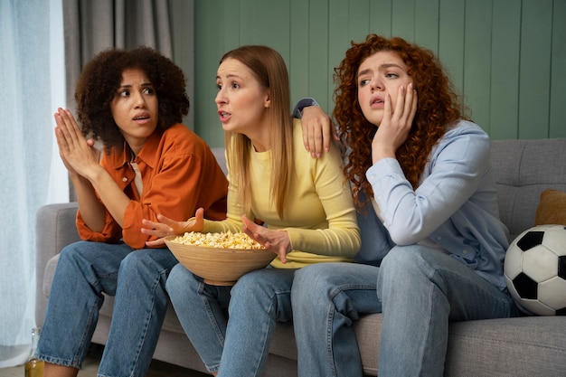 Free photo group of female friends and sports fans watching tv at home together