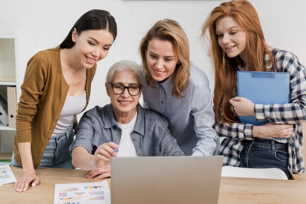 Группа женщин, работающих вместе на ноутбуке