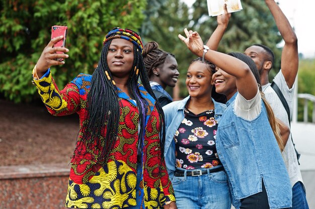 5명의 아프리카 대학생들이 대학 마당 캠퍼스에서 함께 시간을 보내는 그룹 흑인 아프리카 친구들이 전화 교육 테마로 셀카를 찍고 있다