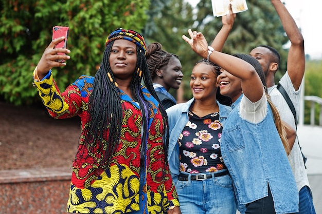 Group of five african college students spending time together on campus at university yard Black afro friends making selfie on phone Education theme