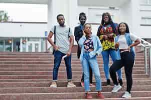 Foto gratuita un gruppo di cinque studenti universitari africani che trascorrono del tempo insieme nel campus del cortile dell'università amici afro neri che studiano il tema dell'istruzione