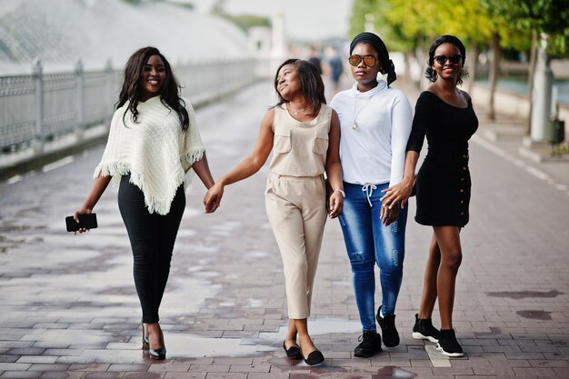 Group of four african american girls having fun against lake with fountains