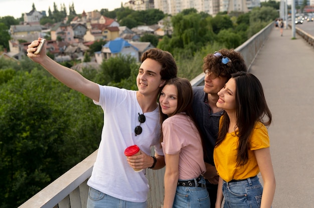 Foto gratuita gruppo di quattro amici che trascorrono del tempo insieme all'aperto e si fanno selfie