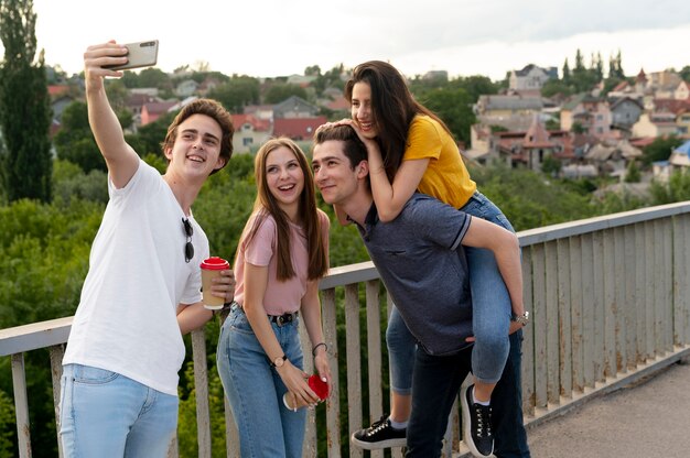 Group of four friends spending time together outdoors and taking selfie