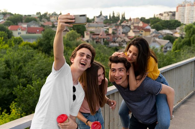 Group of four friends spending time together outdoors and taking selfie