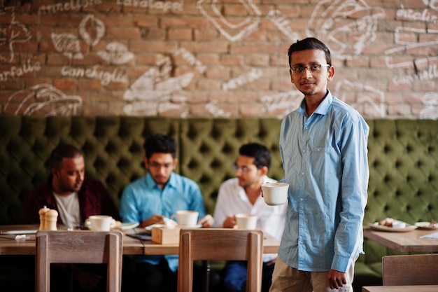 Group of four south asian men's posed at business meeting in cafe Indians work together having conversation Indian man with cup of coffee