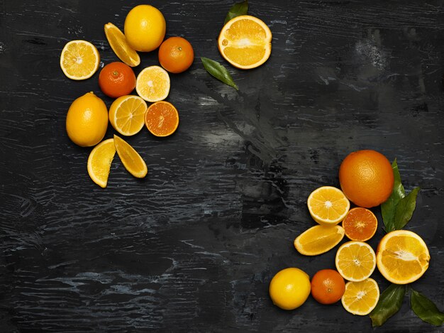 Группа свежих фруктов - лимоны и мандарины на фоне черного пространства