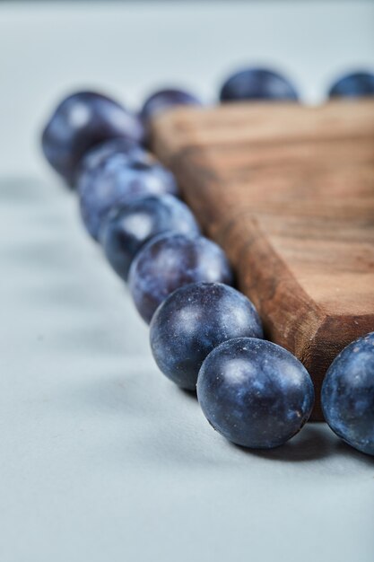 Group of fresh plums around the wooden board.