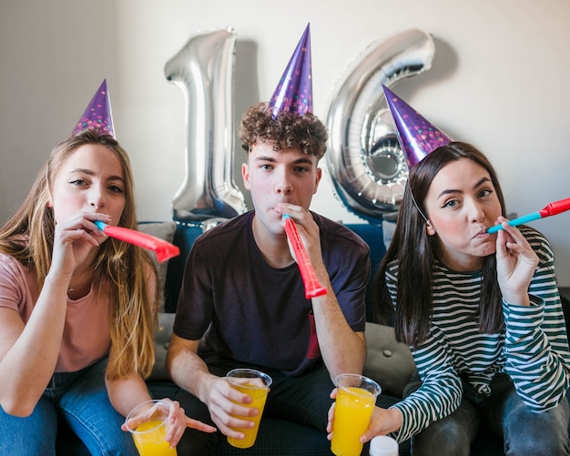 Group of friends blowing party horns