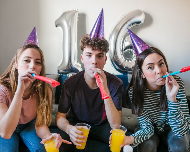 Group of friends blowing party horns