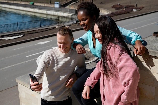 Group of friends celebrating the lifting of face mask restrictions by taking a selfie together outdoors