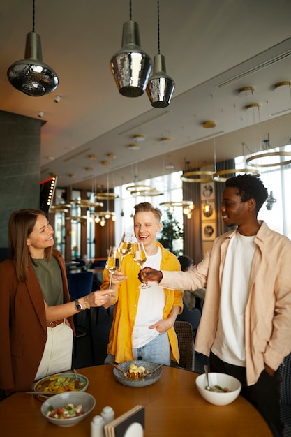 Free photo group of friends cheering with wine glasses at a restaurant