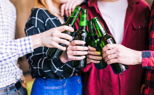 Group of friends clinking bottles of beer