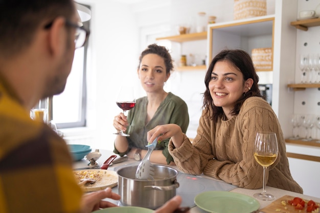 Gruppo di amici che mangiano pasta insieme in cucina