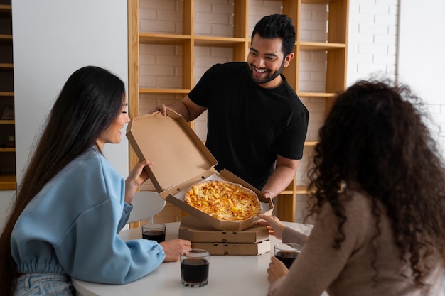 Free photo group of friends eating pizza at home together