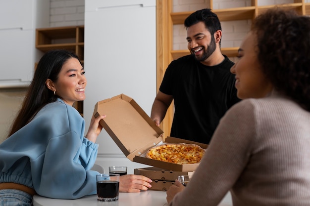 Free photo group of friends eating pizza at home together