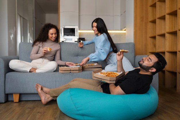 Free photo group of friends eating pizza together at home