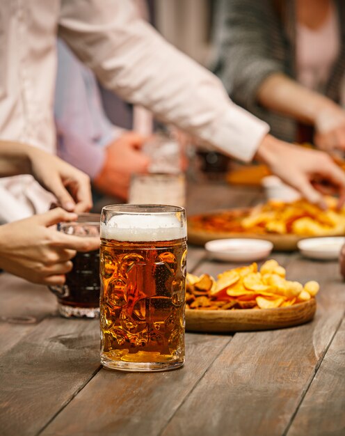 Group of friends enjoying evening drinks with beer on wooden table