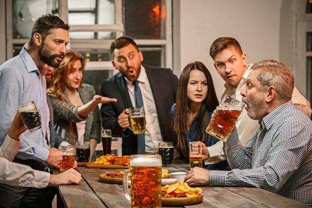 Gruppo di amici che godono di drink serali con birra sulla tavola di legno