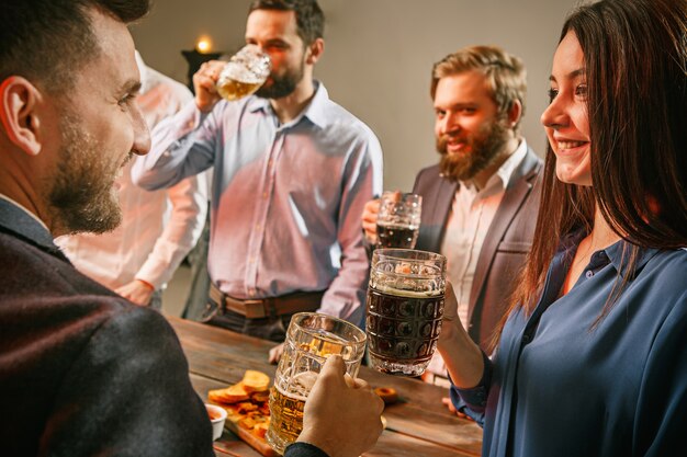 Group of friends enjoying evening drinks with beer on wooden table