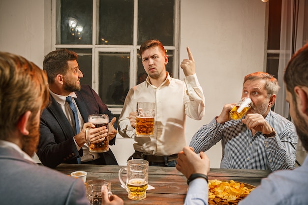 Group of friends enjoying evening drinks with beer on wooden table