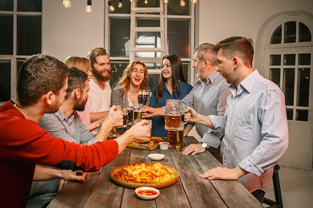 Gruppo di amici che godono di drink serali con birra sulla tavola di legno