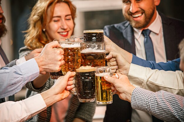 Group of friends enjoying evening drinks with beer on wooden table