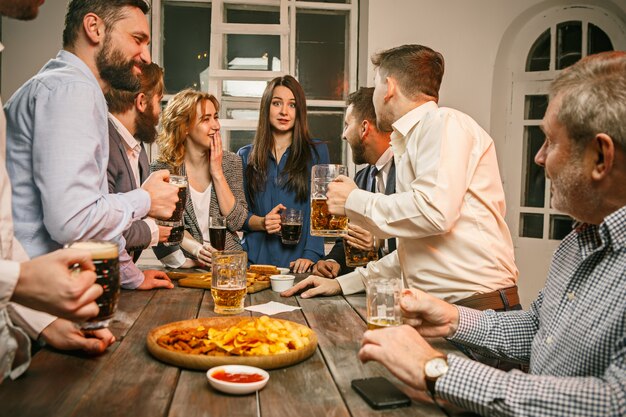 Group of friends enjoying evening drinks with beer on wooden table