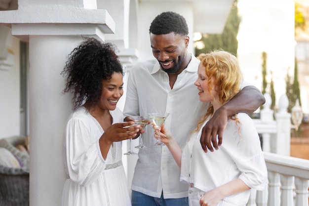 Free photo group of friends having fun during a white party with drinks