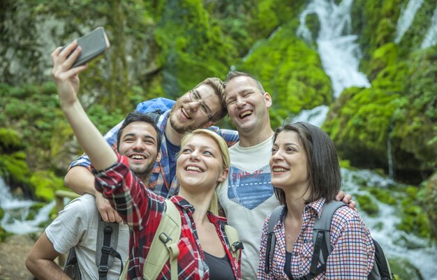 Group of friends having fun and taking selfies in nature