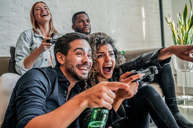 Group of friends having fun while playing video games together at home. Friends concept.