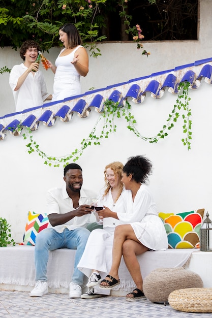 Group of friends having fun during a white party with drinks