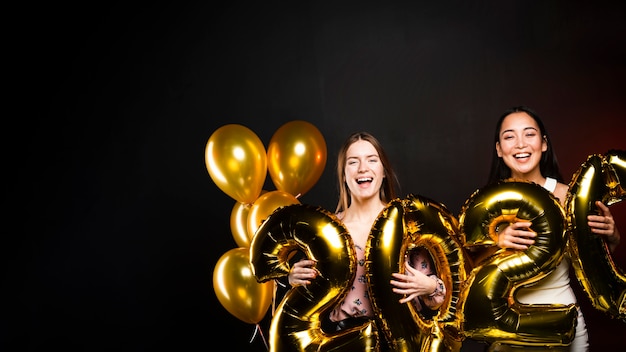 Group of friends holding golden balloons for new years