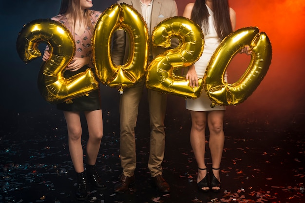 Group of friends holding golden balloons at party