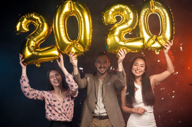 Group of friends holding up new year balloons