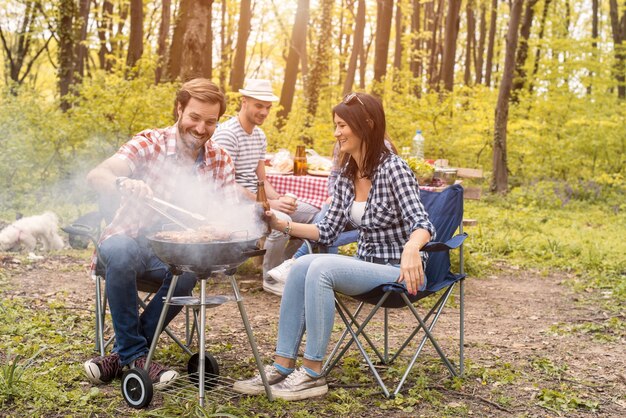 Group of friends making barbecue in the forest at summer