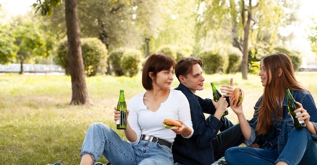 ハンバーガーとビールを持って公園で友達のグループ