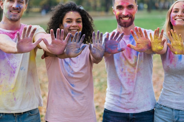 Free photo group of friends posing with colored hands at holi