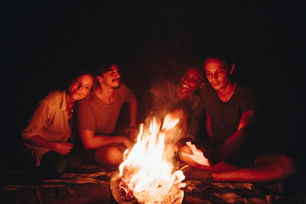 Foto gratuita gruppo di amici seduti intorno a un falò in un campeggio