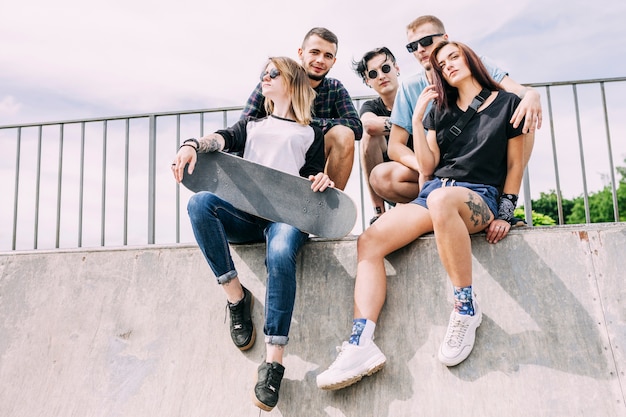 Group of friends sitting on railing with skateboard