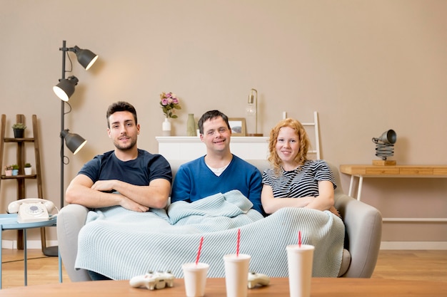 Free photo group of friends on sofa with soda cups and blanket