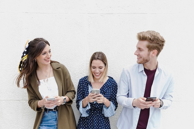 Группа друзей, стоящих возле стены, с помощью мобильного телефона