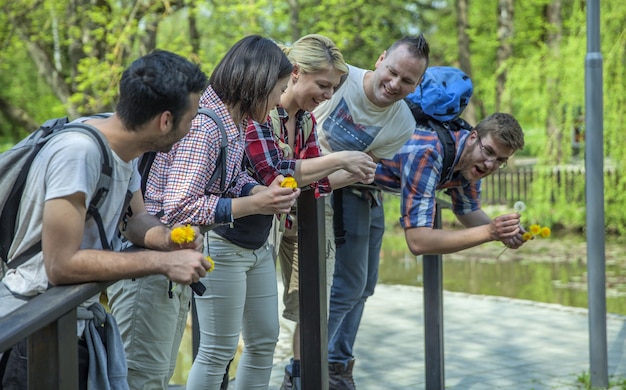 Free photo group of friends standing on small bridge in a park on sunny day